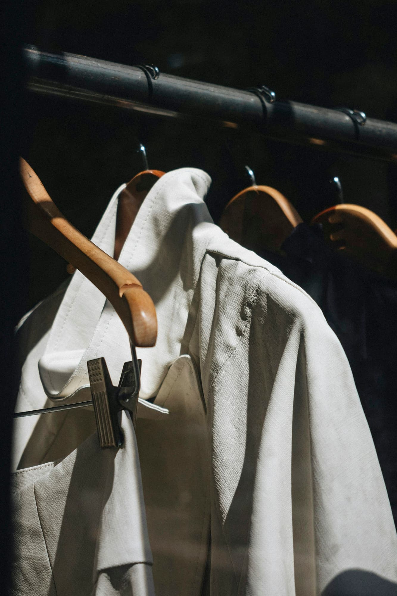 White jacket on a wooden hanger among other clothes